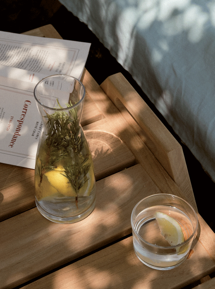 eau-thym-citron-et-livre-posés-sur-table-bois-extérieure